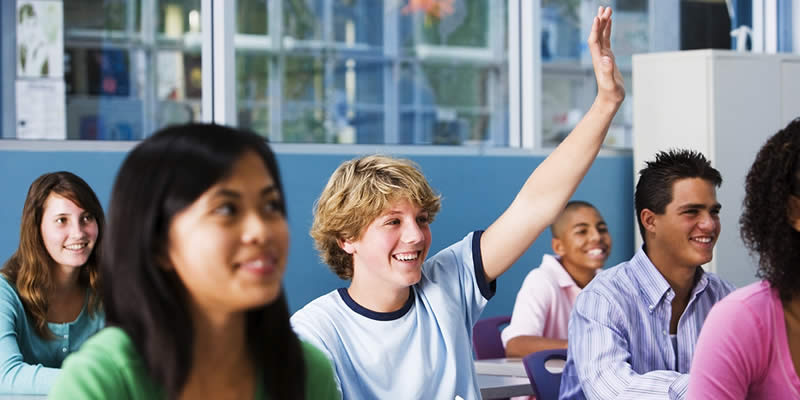 Teens in drug education class, student raising his hand.